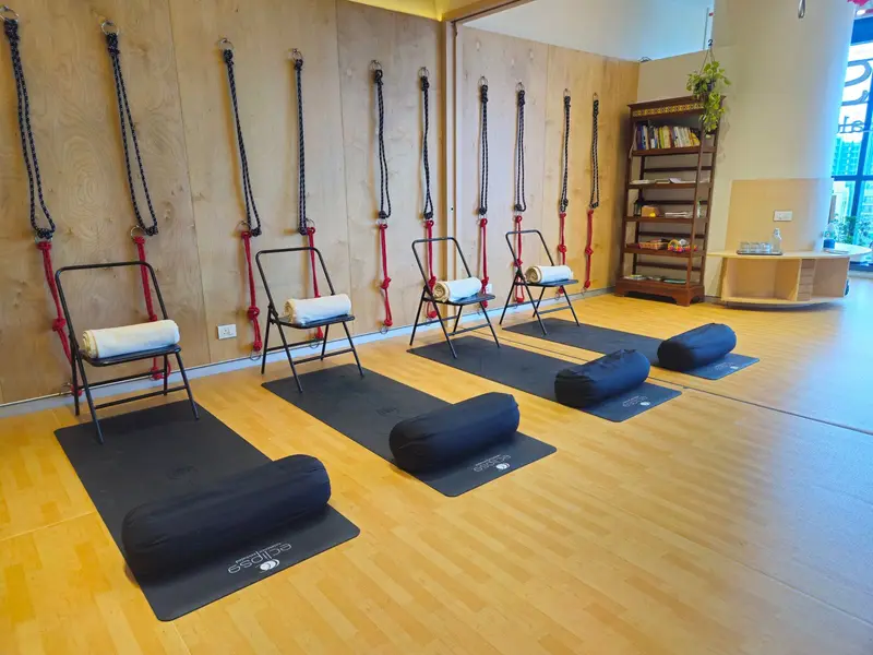 Studio wall with ropes, chairs, bolsters and a bookshelf